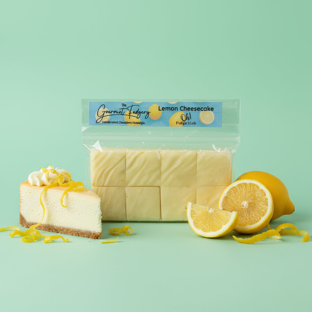 Packaged lemon cheesecake fudge on a mint green background with a slice of Cheesecake and lemon slices