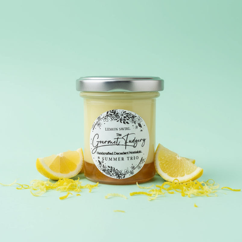 Jar of lemon curd fudge with a decorative label on a mint green background with cut lemons and lemon zest in the foreground.